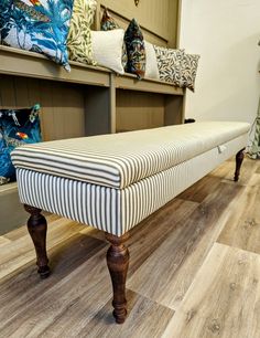 a bench sitting on top of a hard wood floor next to shelves filled with pillows