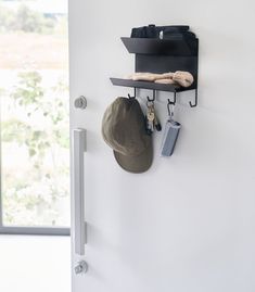 the hat is hanging on the wall next to the coat rack with hats and keys