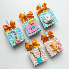 four decorated cookies sitting on top of a white table next to orange ribbons and bows