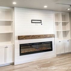 a living room with white bookcases and a fire place in the middle of it