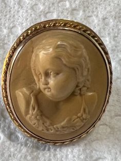 an antique brooch with a small child's head in the center on a white surface