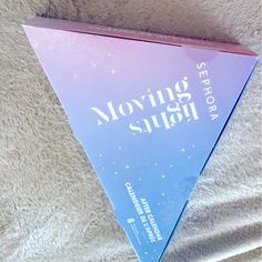 a pink and blue box with the words moving sushi on it sitting on a white blanket