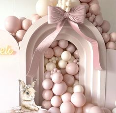 there is a pink and white room with balloons all over the place, including a cat statue