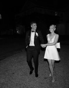 a man and woman are walking together in the dark, dressed in formal attire with their arms around each other