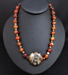 Artisan Statement Necklace~Brown Agate Statement Necklace~Carnelian Southwestern Necklace~Red Carnelian Chunky Necklace~ Handmade Necklace~ This 18" handmade artisan statement necklace features an iridescent artisan SRA focal bead . It is made with 10mm round polished carnelian beads and clear glass disc beads etched in gold.  The colors are a rich rust golden orange with earth tone greens, brown, gold and taupe. Because of its blend of colors, it is difficult to describe it although I think pic Earthy Necklaces As Gifts, Earthy Round Necklaces For Gifts, Handmade Round Earthy Necklaces, Handmade Earthy Round Necklaces, Handmade Round Earthy Necklace, Unique Red Agate Beaded Necklaces, Handmade Red Agate Necklace, Artisan Carnelian Orange Jewelry, Artisan Orange Carnelian Jewelry