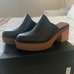 Black Heeled Clogs. Never Worn. Size 8. 2.5” Heel. Black Platform Clogs With Wedge Heel, Modern Black Clogs With Rubber Heel Cap, Black Synthetic Clogs With Wedge Heel, Trendy Black Slip-on Clogs, Black Clogs With Wooden Heel For Work, Black Wedge Heel Clogs For Spring, Black High Heel Platform Clogs, Modern Clogs With Wooden Wedge Heel, Modern Black Mules With Stacked Heel