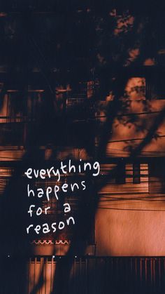 a sign that says everything happens for a reason on the side of a building in front of a tree