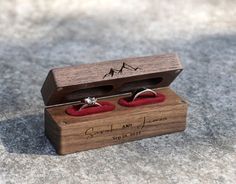 an open wooden box with two wedding rings in it and the inside is red velvet