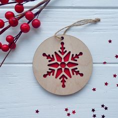 a wooden ornament with a snowflake design on it next to red berries