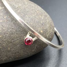 "I designed this simple, elegant and delicate sterling silver bracelet (available in Garnet or Sapphire) for women. in honor of mothers, and grandmothers and sisters, and girlfriends, and wives; in honor of women everywhere! I decided to designed a select number of pieces for women. Don't worry. I still specialize in Jewlery for Men. These are special limited designs for her. More stones varieties coming soon! I hand forged this bracelet in my home studio in Austin, TX. It's made of Sterling sil Minimalist Sterling Silver Hallmarked Bracelet As Gift, Minimalist Hallmarked Sterling Silver Bracelet, Garnet Bangle Jewelry Gift, Garnet Bangle Jewelry As Gift, Modern Sterling Silver Bracelet With Gemstone, Elegant Sterling Silver Bracelet With Birthstone, Modern Garnet Jewelry As A Gift, Modern Garnet Jewelry For Gift, Mens Onyx Bracelet