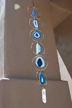 a blue and white beaded necklace hanging from a metal wire on top of a wall