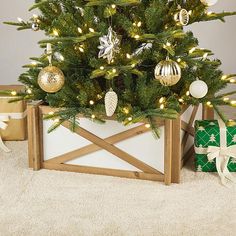 a small christmas tree in a wooden crate with presents around it and lights on the top