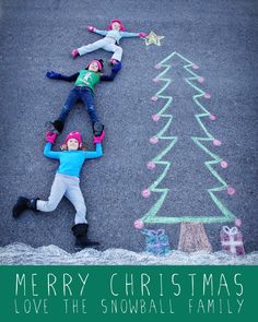 two children laying on their stomachs in front of a christmas tree drawn on the pavement