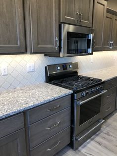 an empty kitchen with granite counter tops and stainless steel stove top oven, microwave and dishwasher