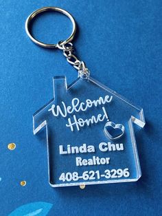 a clear acrylic house keychain with the words, welcome home linda chu realtor