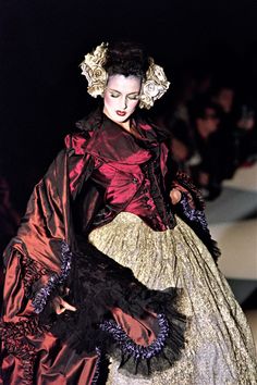 a woman is walking down the runway wearing a dress with ruffles on it