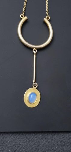 Sterling Silver with gold plate unique and unusual pendulum design necklace with a gorgeous fiery blue Opal cabochon pendant terminal. Minimalist yet ornate. Rolo chain with rollover clasp. Weight is 9.52g Length of chain is 18.5 inches. Opal measures 9mm x 7mm Pendant measure 8.3cm from top to bottom. Gold Teardrop Cabochon Jewelry, Oval Cabochon Brass Necklace, Modern Blue Pendant Jewelry, Modern Jewelry With Round Cabochon Pendant, Modern Cabochon Round Pendant Jewelry, Modern Cabochon Round Pendant, Blue Long Drop Necklace As Gift, Blue Long Drop Necklace As A Gift, Blue Long Drop Necklace For Gift