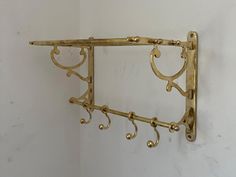 a gold metal shelf with two hooks on the side and one hook attached to it