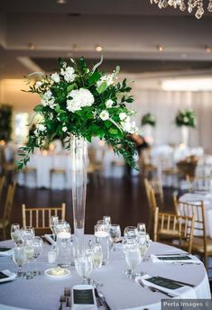 a tall vase filled with white flowers on top of a table