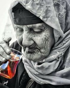 an old woman holding a glass with liquid in it