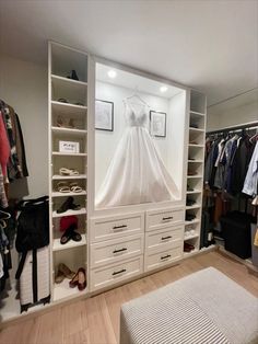 a white closet with clothes and shoes on the shelves in front of it is also a bed