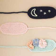 three crocheted items are laying on the floor next to each other, including a sleeping mask