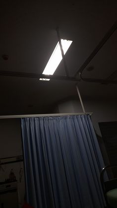 the light is shining on the ceiling in the dark room with blue curtains and drapes