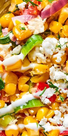 a colorful salad with corn, tomatoes, and feta cheese is shown close up