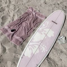 a surfboard laying on the sand next to a towel