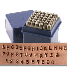 a metal stamp with the letters and numbers on it, in front of a blue box