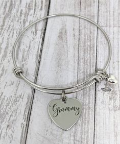 "This is an stainless steel bangle bracelet with an 18mm stainless steel heart charm that reads, \"Grammy.\" All items will arrive boxed and ready for gift giving." Customizable Stainless Steel Jewelry For Mother's Day, Personalized Stainless Steel Jewelry For Mother's Day, Personalized Hypoallergenic Stainless Steel Jewelry, Hypoallergenic Stainless Steel Jewelry For Personalized Gifts, Silver Name Bracelet With Heart Charm For Gift, Heart-shaped Stainless Steel Charm Bracelet For Mother's Day, Silver Name Bracelet With Heart Charm As Gift, Heart-shaped Stainless Steel Bracelet For Mother's Day, Silver Name Bracelet With Heart Charm