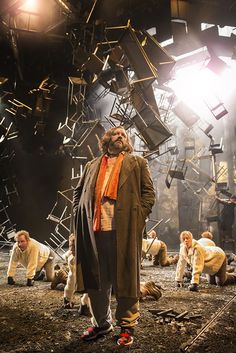 a man standing on top of a dirt field next to a pile of chairs and ladders