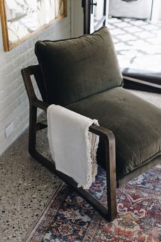 a green chair with a white blanket on it's back in front of a mirror