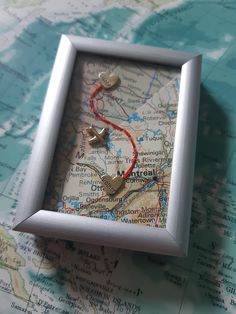 a map with a red string attached to it and two silver hearts in the middle