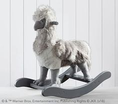 a stuffed llama sitting on top of a wooden rocking toy chair in front of a white wall