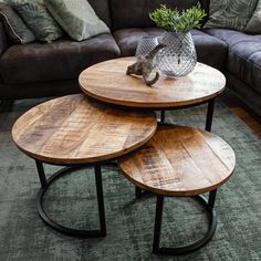 three wooden tables sitting on top of a green rug in front of a brown couch