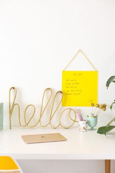 a white desk topped with a yellow sign next to a plant and potted plants