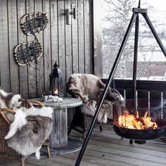 an outdoor fire pit on a deck with two chairs and a table in the background