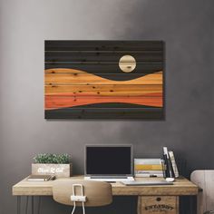 a desk with a laptop computer on top of it next to a wall mounted painting