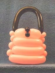 an orange handbag with black handles is on display in a museum case, it appears to be made out of balloons