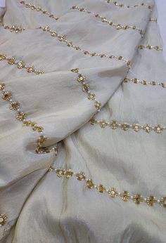 This elegant beige saree is crafted from pure material and features delicate straight-line work with intricate pearl and cutdana embellishments. The subtle yet sophisticated design adds a touch of grace, making it a timeless choice for any occasion. Perfect for those who appreciate minimalistic elegance, this saree exudes refined charm. Fabric of Saree: Pure Material Work: Straight-Line Work with Pearl Embellishments Care: Dry Clean Only Product color may slightly vary due to photographic lighti Elegant Pearl Embroidered Saree For Wedding, Elegant Saree With Pearl Embroidery, Elegant Semi-stitched Saree With Pearl Embroidery, Festive Silk Pre-draped Saree With Pearl Embroidery, Gold Embroidered Saree Fabric, Wedding Saree Indian, Bridal Saree, Saree Wedding, Saree Designs