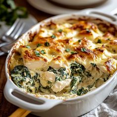 a casserole dish with chicken and spinach in it on a wooden table