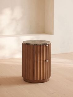 a round wooden table sitting on top of a hard wood floor next to a window