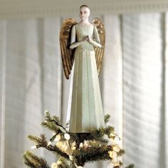 an angel figurine sitting on top of a christmas tree in front of a window