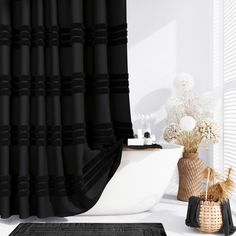 a black and white bathroom with a tub, rug and flower arrangement in front of the shower curtain