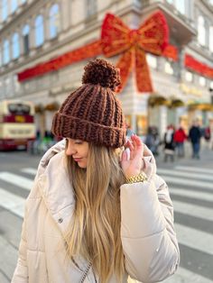 a woman is walking down the street wearing a brown hat and coat with a big bow on it