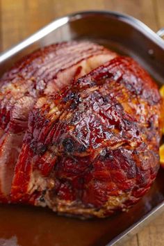 a large piece of meat sitting on top of a pan next to some vegetables and fruit