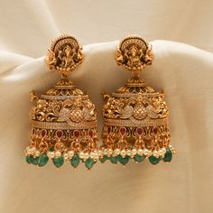 Description: Indulge in the epitome of elegance with our captivating antique gold-plated 925 silver jhumka earrings. Masterfully handcrafted, these earrings feature intricate peacock and floral motifs, dazzling Kempu stones, CZ stones, and bead drops. The stud part features the Goddess Lakshmi motif each detail reflects timeless luxury and charm. Product Information: Metal: 925 Silver with Antique Gold Plating Length: 5cm Stones: High Grade CZ Stones Findings: Push back Latest Design Earrings Gold, Gold Wedding Earrings Indian, Lakshmi Jhumkas Gold, Gold Antique Jhumkas, Cz Earrings Indian Gold, Temple Jewellery Earrings Antique, Jumka Earrings Gold Indian Jewelry, Temple Earrings Gold Jewelry, Antique Gold Jhumka