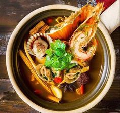 a bowl filled with soup and shrimp on top of a wooden table