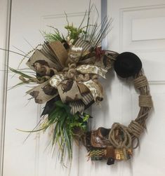 a wreath is hanging on the front door with cowboy boots and hats attached to it